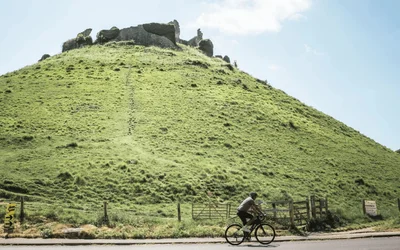 Image of cyclist riding past the ruins of Corfe Castle